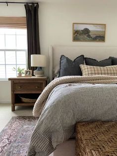 a bed room with a neatly made bed next to a window and a painting on the wall