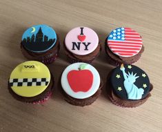 six cupcakes decorated with different designs on top of a wooden table in the shape of usa, new york, statue of liberty, i love ny