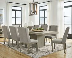 a dining room table and chairs in front of large windows