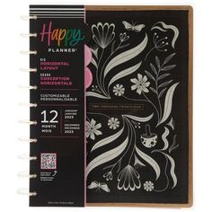 a black and white planner with flowers on the cover, sitting next to a notepad