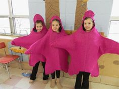 three girls in pink ponchies standing next to each other