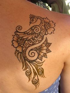 the back of a woman's shoulder with henna tattoos on it