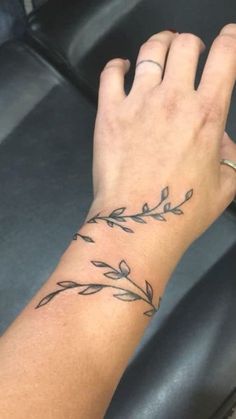 a woman's hand with a small tattoo on her left wrist and an olive branch in the middle