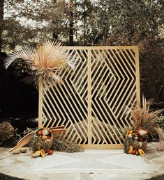 a table topped with two vases filled with flowers and plants next to a wooden screen