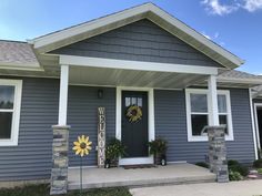 a gray house with white trim and sunflowers on the front door is shown