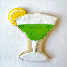 a cookie shaped like a margarita glass with lime and lemon wedges on the rim