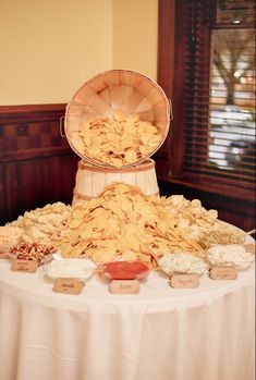 a table topped with lots of food on top of a white cloth covered round table