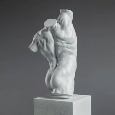 a white sculpture is standing on top of a block in front of a gray background