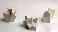 three sculptures made out of concrete sitting on top of a white table next to each other