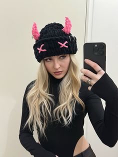 a woman taking a selfie in front of a mirror wearing a black hat with pink ears