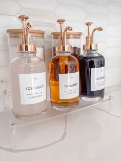 three soap dispensers sitting on a glass shelf