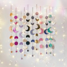 a wall hanging made out of different colored circles and crescents with string lights around it