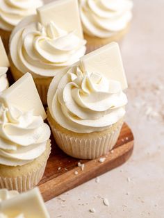 cupcakes with white frosting on a wooden board