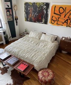 a bed sitting on top of a hard wood floor next to a table with books