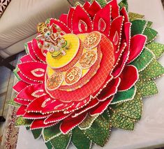 an intricately designed paper flower is displayed on a white table with red and green leaves