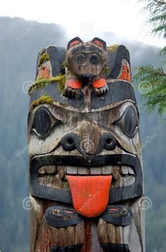 a totema carved into the side of a tree trunk with mountains in the background