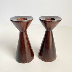 two wooden candlesticks sitting on top of a white table next to each other