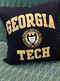 a black and gold pillow with the words georgia tech on it sitting on a green chair