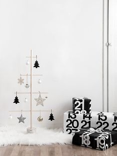 a white christmas tree with black and silver ornaments next to two presents on the floor