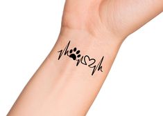 a person's wrist with a dog paw and heart tattoo on it