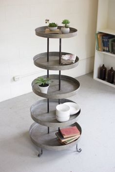 three tiered trays with plants and books on them in the corner of a room