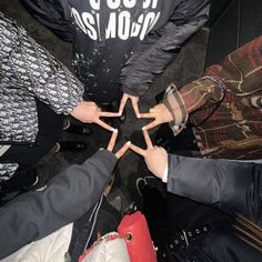 four people standing in a circle with their hands together