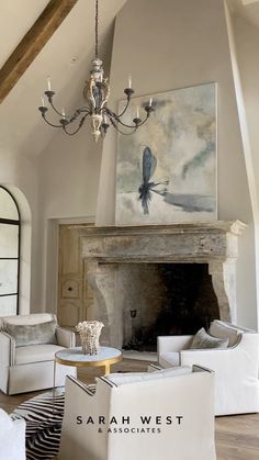 a living room filled with furniture and a chandelier hanging from the ceiling over a fire place