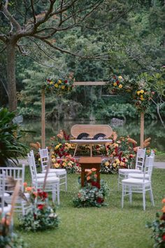 an outdoor ceremony set up with white chairs and flowers on the ground, surrounded by greenery