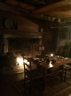 a dining room table with candles lit in front of an open fire place next to a fireplace