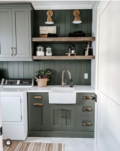 a kitchen with green painted cabinets, white appliances and wooden shelves on the wall above the sink