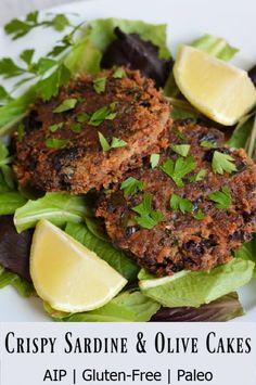 two crab cakes with lettuce and lemon wedges on a bed of greens