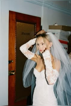 a woman in a wedding dress and veil is posing for the camera with her hands on her head