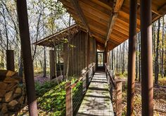 the walkway is lined with wooden posts and railings, leading to a cabin in the woods