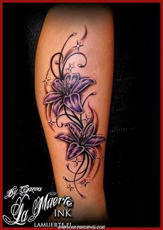 a woman's leg with purple flowers and vines on the side of her thigh