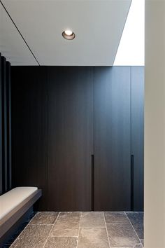 a bathroom with black walls and tile flooring next to a white bench in the corner