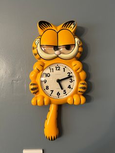 a yellow tiger clock mounted to the side of a wall with glasses on it's face