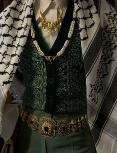 a mannequin dressed in green and white clothing with gold jewelry on it's neck