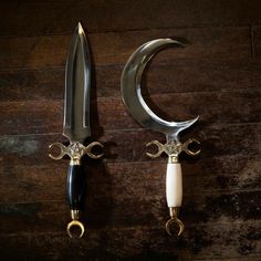 two knifes are sitting next to each other on a wooden table with metal handles