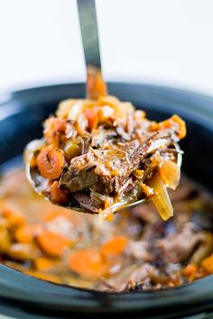 a spoon full of stew with carrots and meat