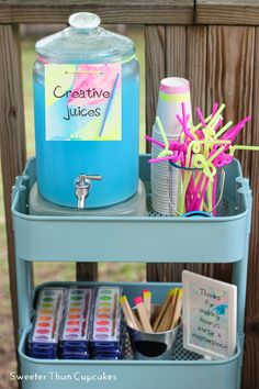 a blue container filled with craft supplies on top of a shelf next to a wooden fence