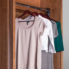 three shirts hanging on a wooden closet door