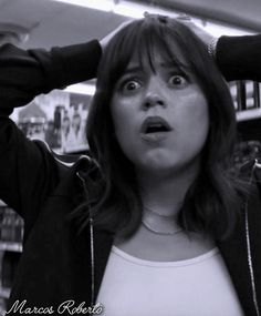 a woman holding her hair up in the air with one hand on her head and looking surprised