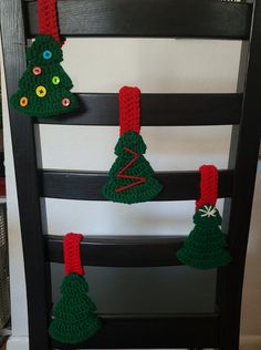 three crocheted christmas trees hanging from a chair