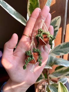 someone is holding two tiny crocheted strawberries in their palm tree - like hands