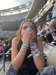 a woman covers her face with both hands at a baseball game while sitting in the bleachers