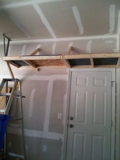 an unfinished room with white walls and a ladder in front of the door that is being installed