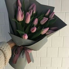 a person holding a bouquet of pink tulips