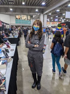 a woman wearing a face mask and standing in front of a table full of books