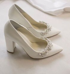 two white high heels with pearls on them