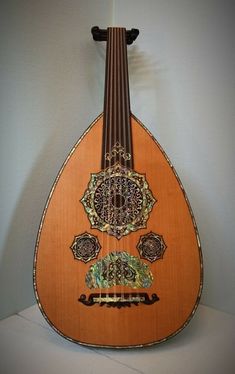 an orange and black instrument with intricate designs on it's back end, against a white wall